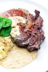 beef steak with sauce, mashed potatoes and spinach leaves