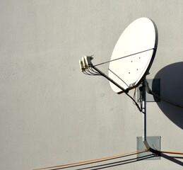 Satellitenschüssel hängt an einert Hauswand und wirft dort einen Schatten