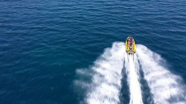 Aerial drone video of jet ski watercraft operated by stunt man speeding in deep blue open ocean sea