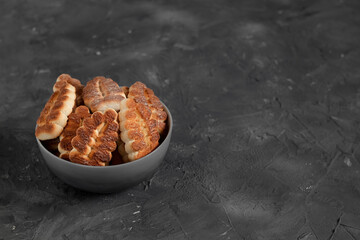 Grey bowl with delicious tree shaped cookies on a dark grey background. Fresh butter biscuits. Copy space.