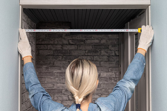 Woman measuring a doorway with a tape measure. woman using a tape measure (Corrected).