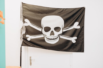 Black pirate flag with skull and crossbones on a white door. Halloween decor