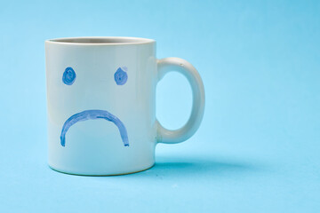 Blue monday, cup of coffee with a sad face.