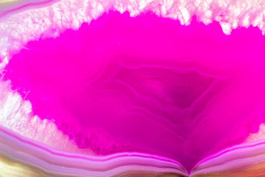 Hot pink and semi-transparent agate geode slice crystal, banded chalcedony stone isolated on a white background surface with lots of detail. Abstract pink crystal image with lots of copy space
