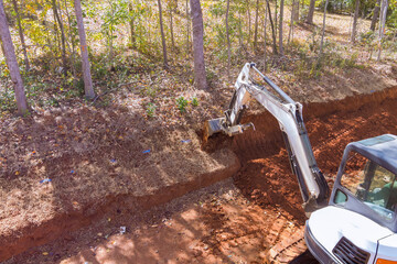Construction site excavation buckets of crawler excavator digging into ground during earthmoving...