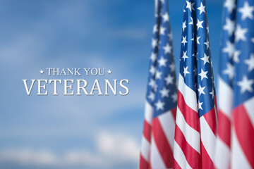 American flags with Text Thankx You Veterans on blue sky background. American holiday banner.
