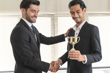 The hands of an employee receiving a golden cup reward from the company manager represent his...