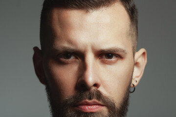 Male beauty concept. Portrait of 30-year-old man standing over dark gray background. Hair brushed...