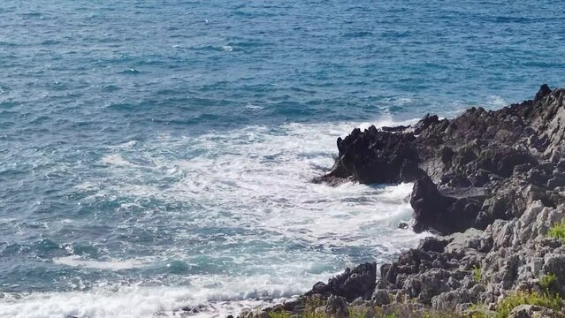 Ocean Waves Collides with Large Rocks Breaking on the Edge of Rocks on the Tropical Coast of Diamante, in Calabria, Illuminated by the Italian Sun.