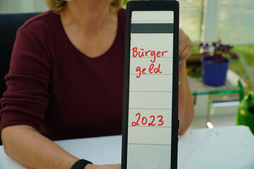 Frau hält einen Ordner mit der Aufschrift Bürgergeld 2023 