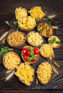 Variety of raw, uncooked pasta in the bowls on the wooden table
