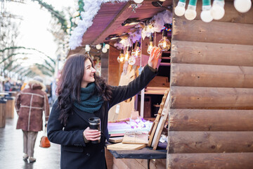 Happy woman buys gifts at festive Christmas market. Concept of winter holidays.