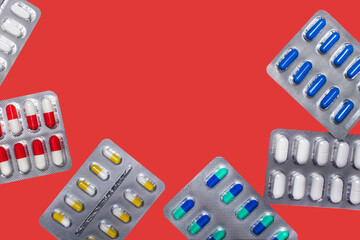 Pills in plastic packaging on a red background.