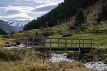 Fototapeta na wymiar Wooden old bridge across the stream in Switzerland Alps 