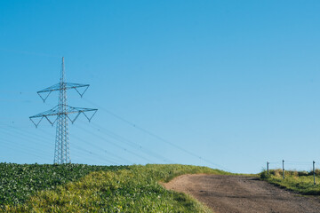 Strommast auf Feld vor blauem Himmel
