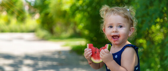 A child eats watermelon in the park. Selective focus.