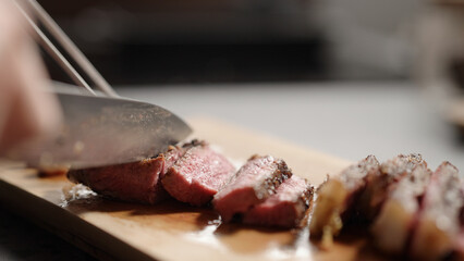 man slicing new york steak on olive wood board