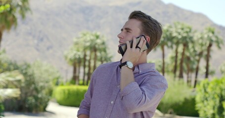 Close up on handsome young man turned to side while listening on a cellphone in Palm Springs,...