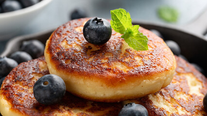 Cottage cheese pancakes served in cast iron frying pan with blueberries and mint leaves. Healthy breakfast food.