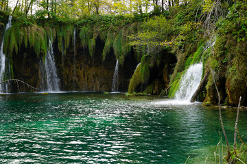 A bay with turquoise lake water and small waterfalls in a deep forest