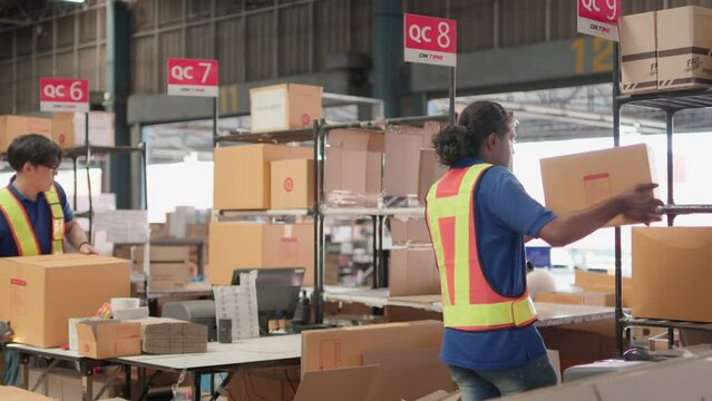 Two asian warehouse worker working checking package products in warehouse, logistic. While staff used laser barcode scanner on cardboard box, distribution center, placement in storage for shipping.