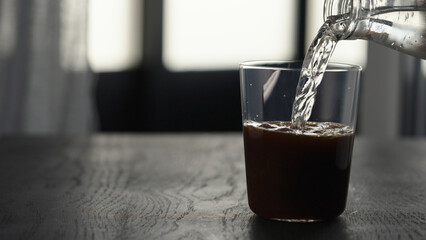 Making espresso tonic in tumbler glass, pour tonic