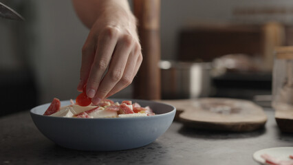 add cherry tomatoes to fusilli pasta in blue bowl
