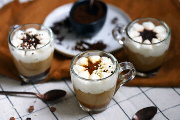 Small mugs with a three-layer coffee-caramel dessert. Delicious pudding in glass cups.