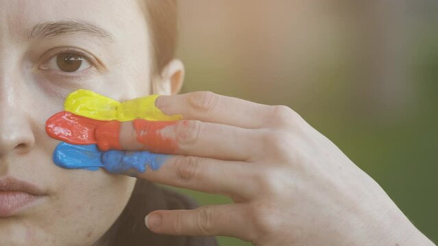 Supporter Painting Face and Looking at Camera. Football Fan Preparing for the Match. Colored Face with Flag Colors Yellow, Blue and Red. Slow Motion 4K Prores 422