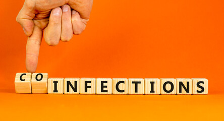 Coinfections or infections symbol. Concept words Coinfections and Infections on wooden cubes. Doctor hand. Beautiful orange background. Medical coinfections or infections concept. Copy space.