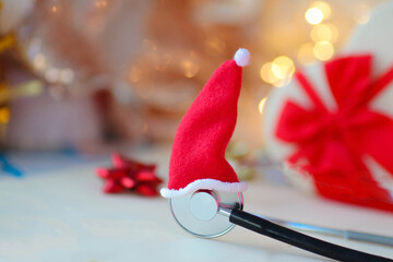 Stethoscope in a santa hat on a background of blur garlands. Health concept for New Year and...