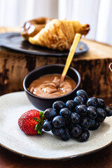 Tábua de doces com doce de leite, uva, morango, croissant, donut e drink