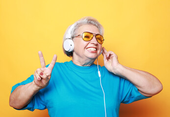 Elderly woman listening to music and show victory sign