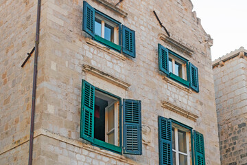 Fototapeta na wymiar Details of walls and windows of yellow, orange and brown houses as seen in sunny day in Dubrovnik, Croatia. September, daytime. Abstract vintage or travel background.