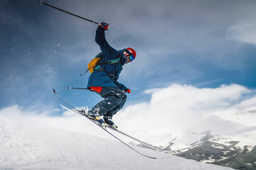 male skier jumping from mountain creating snow plume, winter extreme sport, downhill skiing