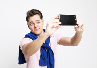 Portrait of a handsome young man taking a selfie isolated over white background