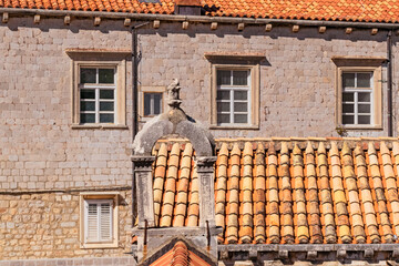 Details of walls, roof tiles and windows of yellow, orange and brown houses as seen in sunny day in...
