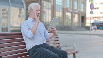 Online Video Chat on Tablet by Old Man Sitting Outdoor on Bench