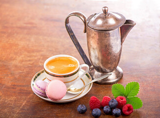 coffee and macarons with berries on a wooden table on a wooden background