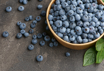 Freshly picked blueberries in a wooden bowl on a wooden background. Healthy food and nutrition.