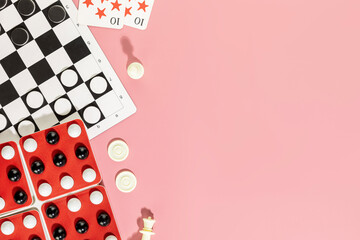 Board games background. Various board games with chess pieces, checkers and playing cards on a pink background copy space. Vacation at home with family. Flat lay