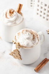Two mugs of Cocoa topped with whipped cream and cinnamon. White ceramic mug mock up with winter xmas new year decorations and copy space