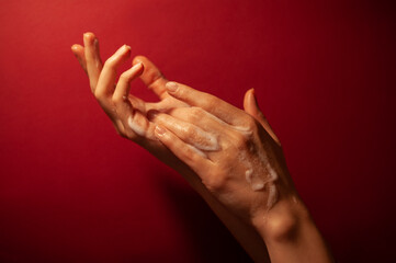 Hands in soap on a dark burgundy background.