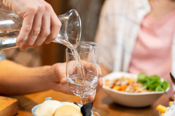food, leisure and people concept - close up of male hands having dinner at restaurant and pouring...