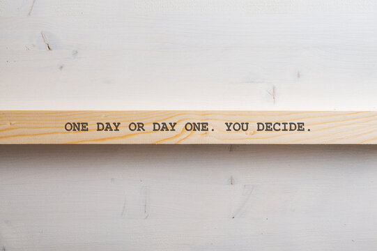 One day or day one. You decide. sign written on a wooden slat