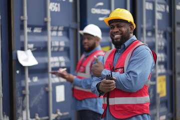 Dock worker man in safety vest work in container port terminal. male Industrial Engineer in Hard Hat, High-Visibility Vest Working. Inspector or Safety Supervisor in Container Terminal. shipping yard.