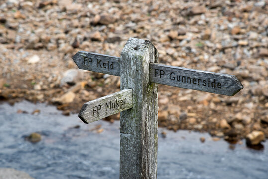 Wooden sign showing the direction to Kled, Muker and Gunnerside at the river swale in the Swaledale in Yorkshire, UK.