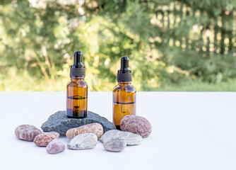 Two brown bottles of essential oil, essence, serum for women's skin care on a natural background....