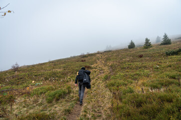 Fototapeta na wymiar A man with a backpack on his back walks along the path, the top of the mountain, fog, cloudy. Recreation. Selective focus, nature
