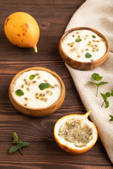 Yoghurt with granadilla and mint in wooden bowl on brown wooden, side view.